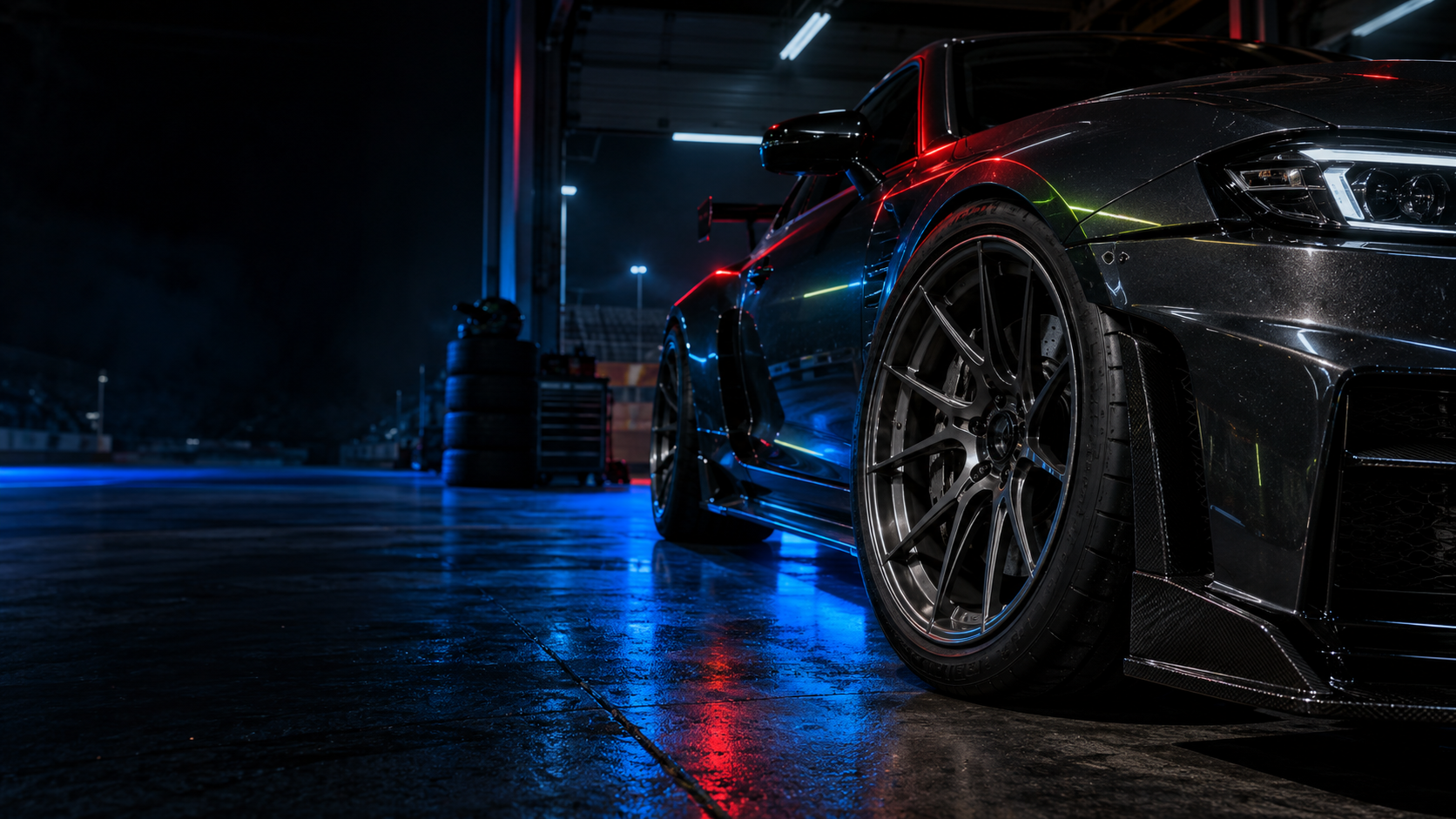 A dark sports car and alloy wheel in a garage with red and blue lighting, from Wheel Sizer